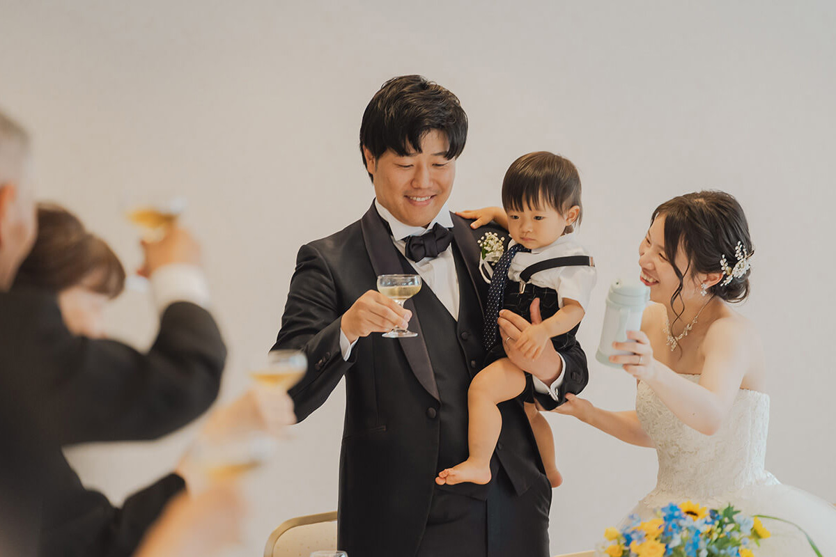 新郎新婦が子供を抱きながら乾杯をする