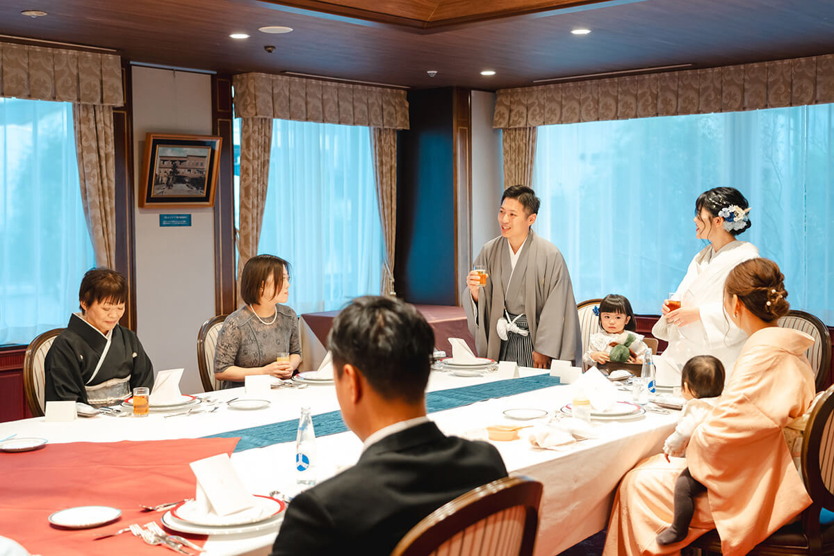 大正ロマン風の会食会場で和装の新郎新婦が乾杯の挨拶をしている