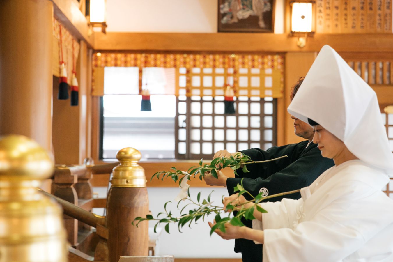 今治城内鎮座 吹揚神社で挙げられたお客様の結婚式写真　神前式で玉串奉奠を行う紋付袴姿の新郎様と白無垢綿帽子をつけた新婦様