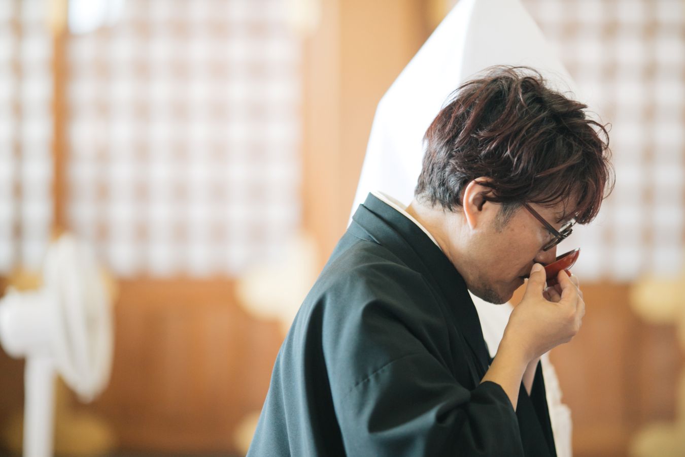 今治城内鎮座 吹揚神社で挙げられたお客様の結婚式写真　神前式で三々九度を行う紋付袴姿の新郎様と白無垢綿帽子をつけた新婦様