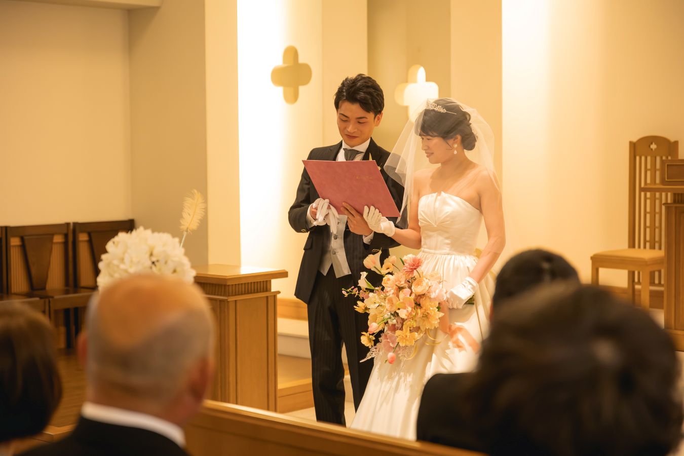 ANAクラウンプラザホテル松山でご結婚式を挙げられたお客様の写真　チャペルで誓いの言葉を読むタキシードウェディングドレス姿の新郎新婦様