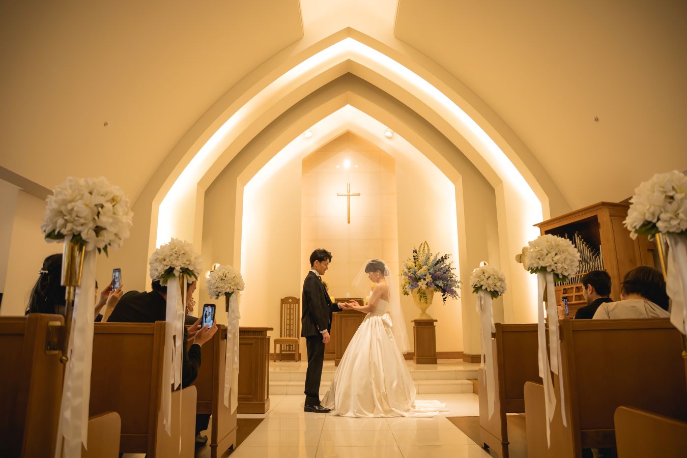 ANAクラウンプラザホテル松山でご結婚式を挙げられたお客様の写真　チャペルで指輪の交換を行うタキシードウェディングドレス姿の新郎新婦様