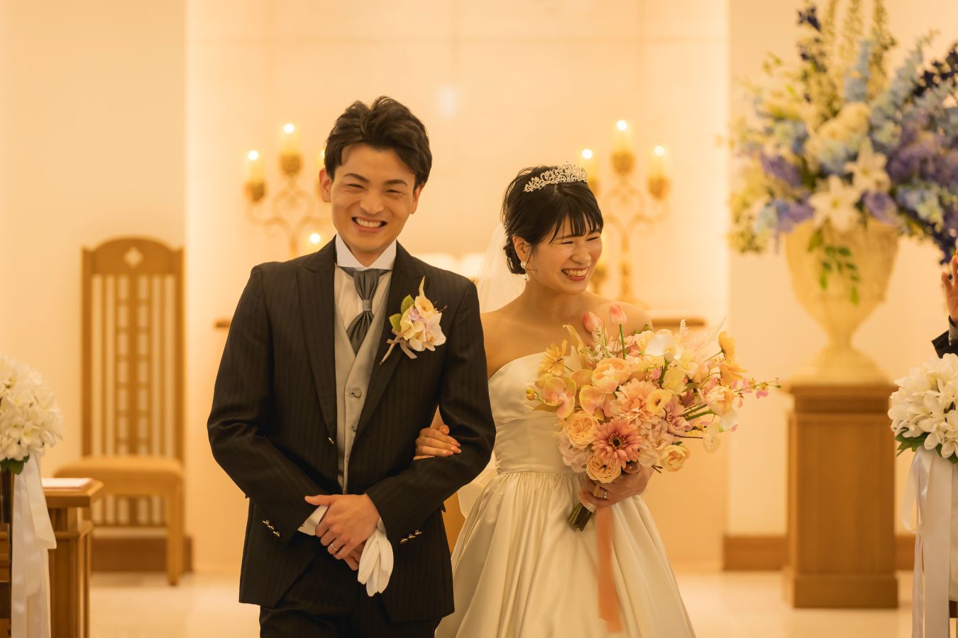 ANAクラウンプラザホテル松山でご結婚式を挙げられたお客様の写真　笑顔でチャペル退場をされるタキシードウェディングドレス姿の新郎新婦様