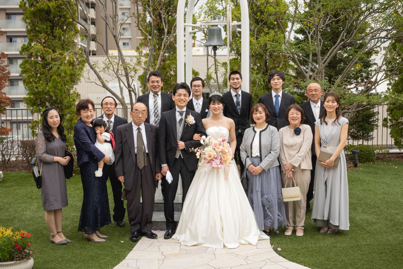 ANAクラウンプラザホテル松山でご結婚式を挙げられたお客様の写真　ガーデンでご家族写真を撮るタキシードウェディングドレス姿の新郎新婦様