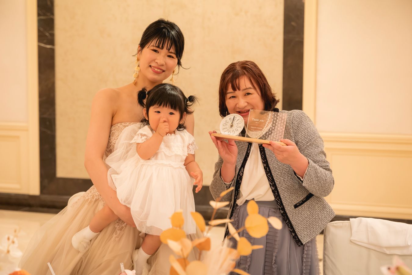 ANAクラウンプラザホテル松山でご結婚式を挙げられたお客様の写真　お母様へ記念品の時計をプレゼントして感謝の気持ちを伝えたカラードレス姿の新婦様とお子様
