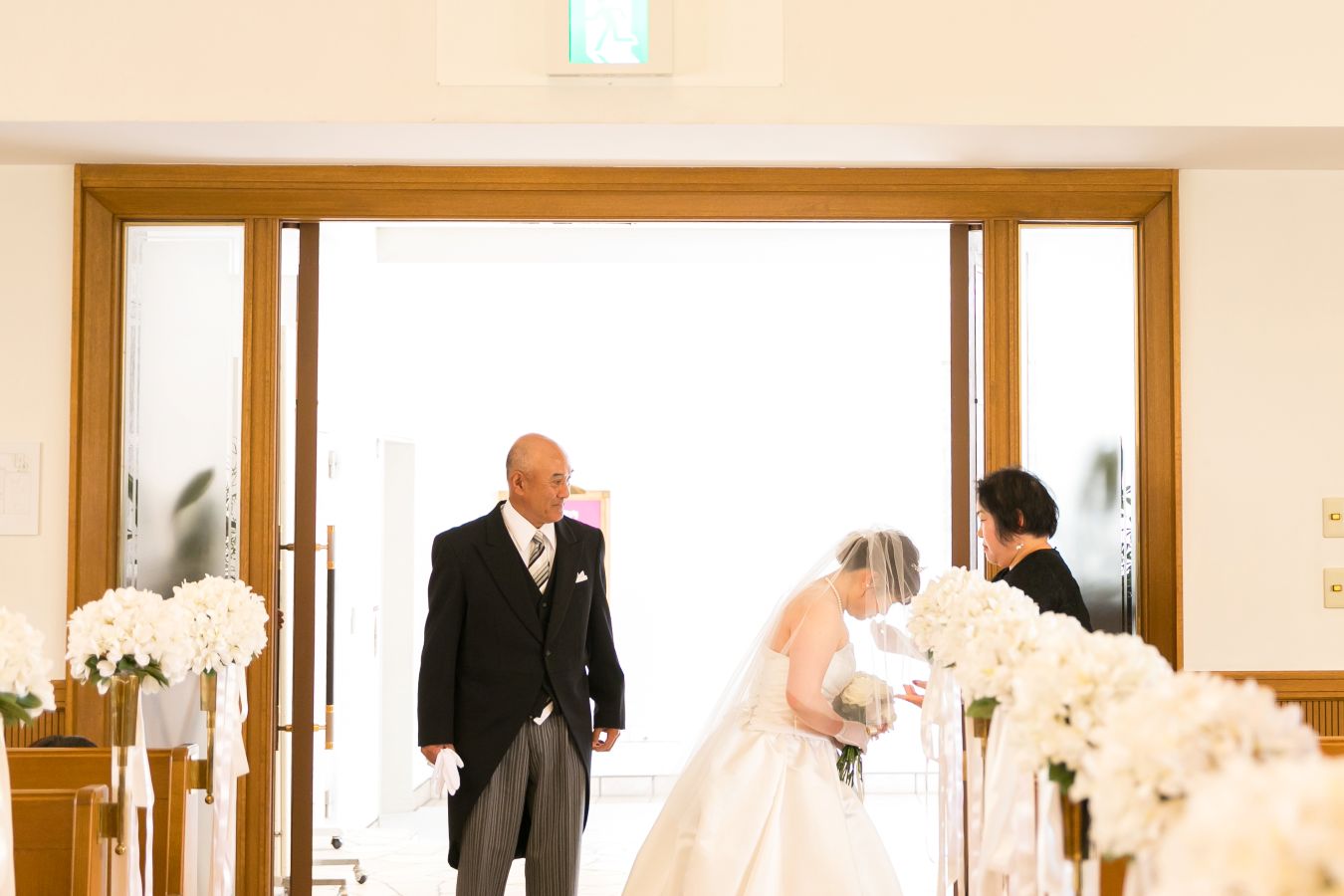 ANAクラウンプラザホテル松山でご結婚式を挙げられたお客様の写真　お母様にベールダウンをしてもらうウェディングドレス姿の新婦様見つめるお父様