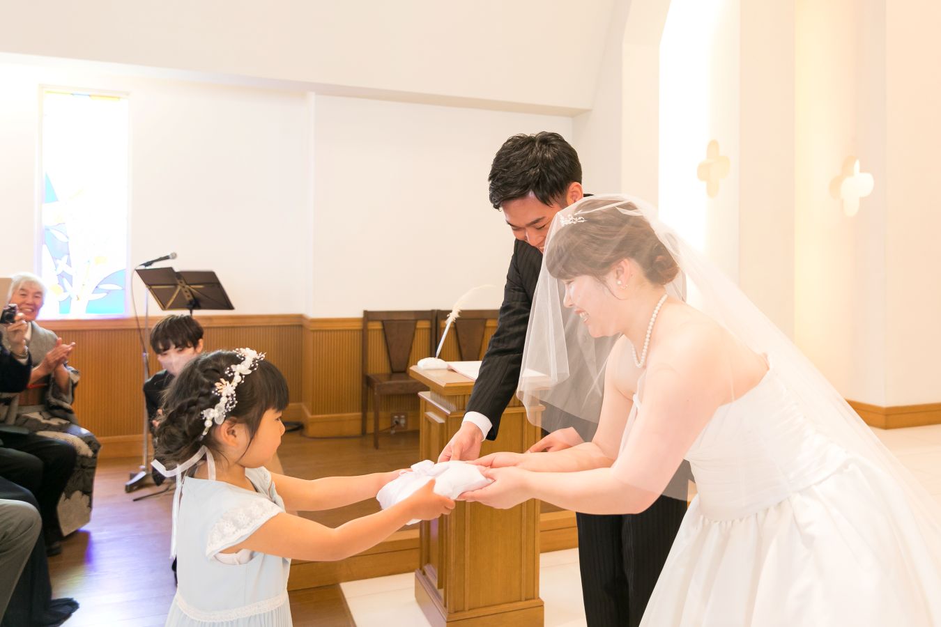 ANAクラウンプラザホテル松山でご結婚式を挙げられたお客様の写真　練習通り指輪を運んでくれたリングガール受け取るタキシードウェディングドレス姿の新郎新婦様