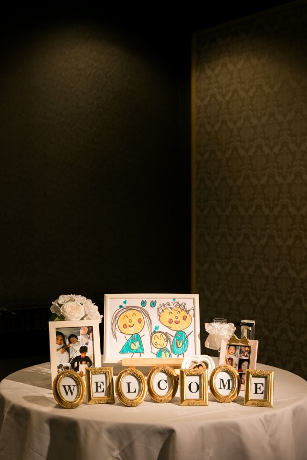 ANAクラウンプラザホテル松山でご結婚式を挙げられたお客様の写真　会食会場前に飾られたウェルカムグッズ思い出の写真やお子様が書いた家族の絵を飾っています