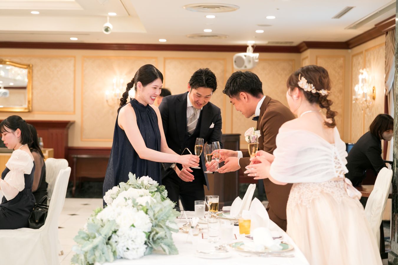 ANAクラウンプラザホテル松山でご結婚式を挙げられたお客様の写真　タキシードカラードレス姿の新郎新婦様へお酌に来てくれたゲスト様