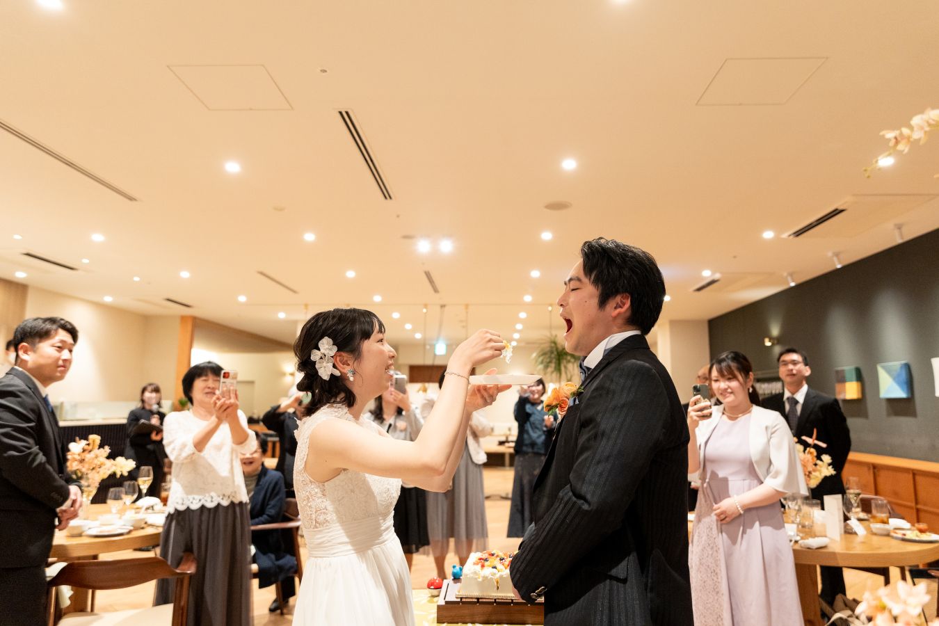 HOTEL LEPO CAHAL レストランAINOでご結婚式を挙げられたお客様の写真　ご家族様に見守られファーストバイトをするタキシードウェディングドレス姿の新郎新婦様
