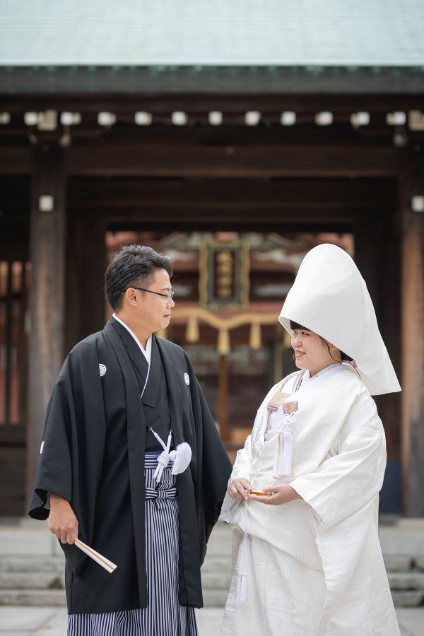 今治城内鎮座 吹揚神社で挙げられたお客様の結婚式写真　神社の前で見つめあう紋付袴白無垢姿の新郎新婦様