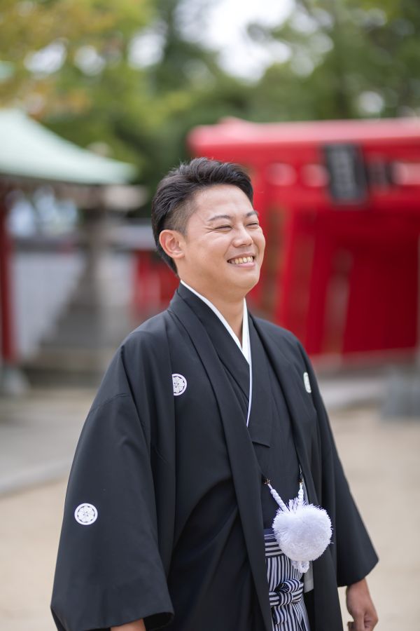 今治城内鎮座 吹揚神社で挙げられたお客様の結婚式写真　ご家族様へ笑顔を向ける紋付袴姿の新郎様