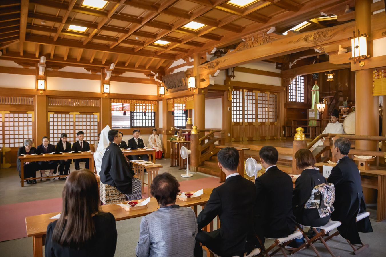 今治城内鎮座 吹揚神社で挙げられたお客様の結婚式写真　ご家族様に見守られ神前式を行っている紋付袴白無垢姿の新郎新婦様