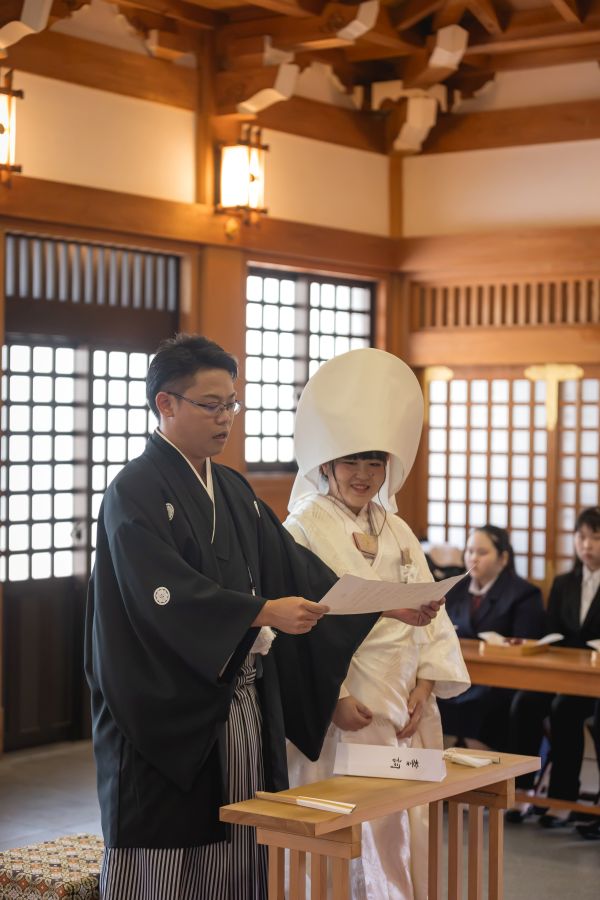 今治城内鎮座 吹揚神社で挙げられたお客様の結婚式写真　神前式で誓いの言葉を読んでいる紋付袴白無垢姿の新郎新婦様