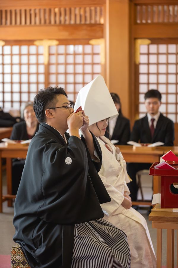 今治城内鎮座 吹揚神社で挙げられたお客様の結婚式写真　神前式で三々九度をする紋付袴白無垢姿の新郎新婦様