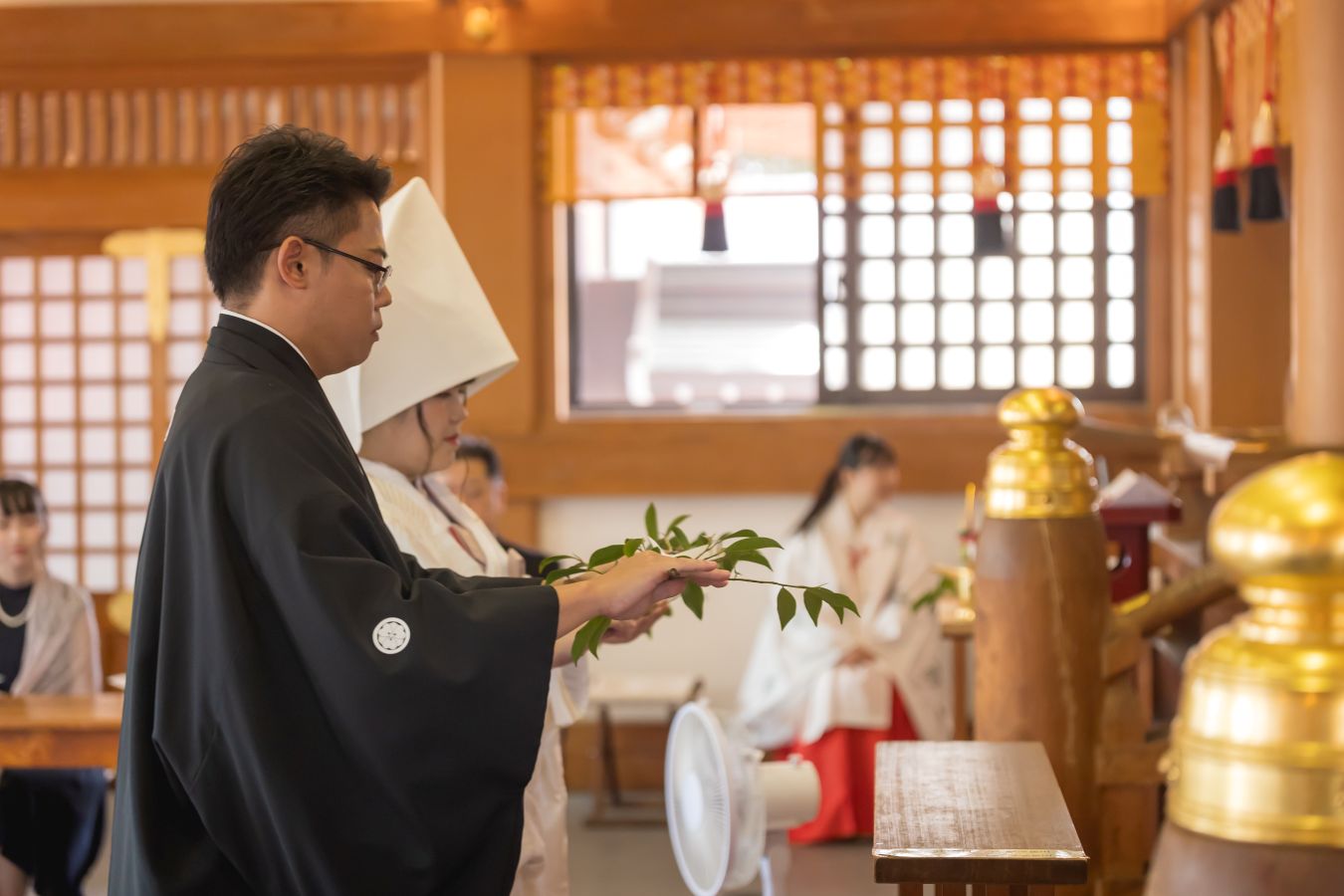 今治城内鎮座 吹揚神社で挙げられたお客様の結婚式写真　神前式で玉串奉奠をしている紋付袴白無垢姿の新郎新婦様