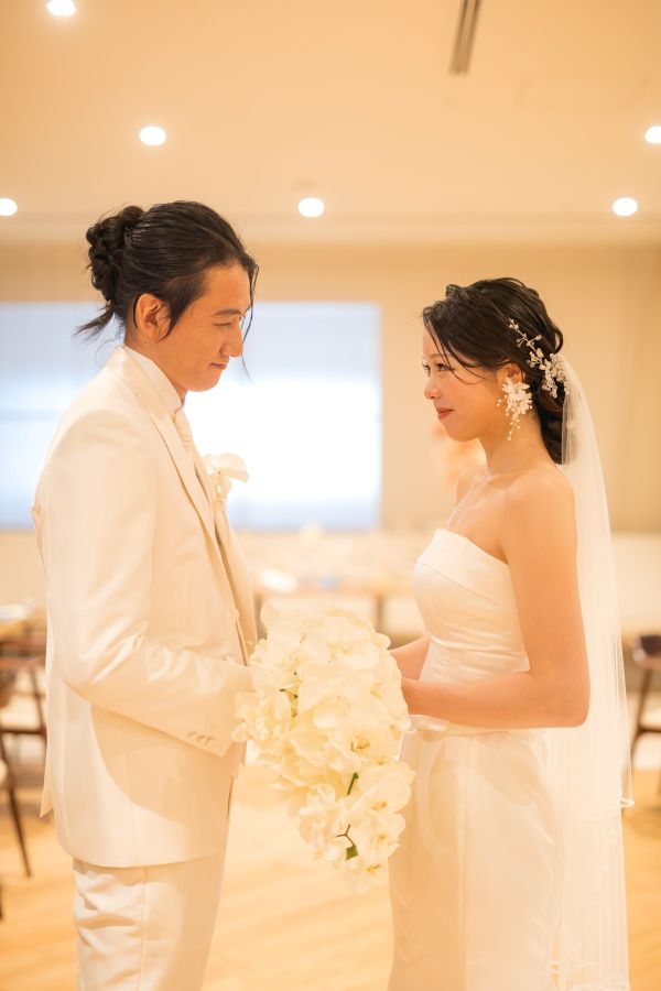 HOTEL LEPO CAHAL レストランAINOでご結婚式を挙げられたお客様の写真　レストラン内でブーケを一緒にもって見つめあうタキシードウェディングドレス姿の新郎新婦様