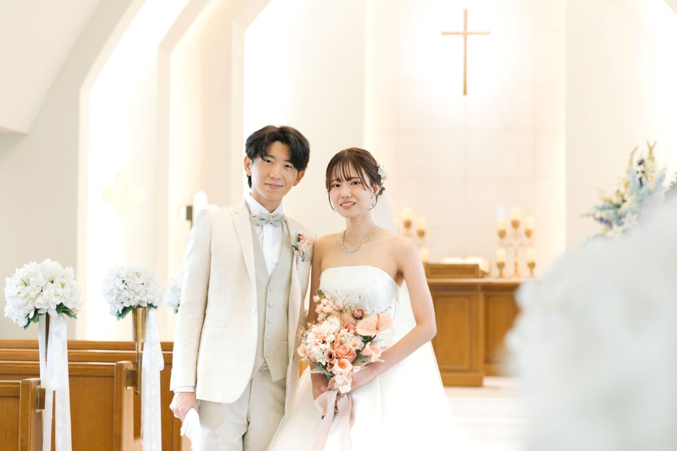 ANAクラウンプラザホテル松山でご結婚式を挙げられたお客様の写真　チャペルで寄り添ういあうタキシードを着た新郎様とウェディングドレスを着てブーケを持った新婦様
