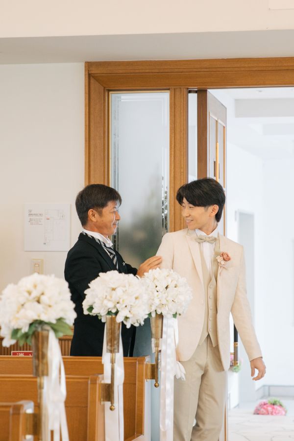 ANAクラウンプラザホテル松山でご結婚式を挙げられたお客様の写真　新郎様の入場シーン　ジャケットを着せてもらう新郎様