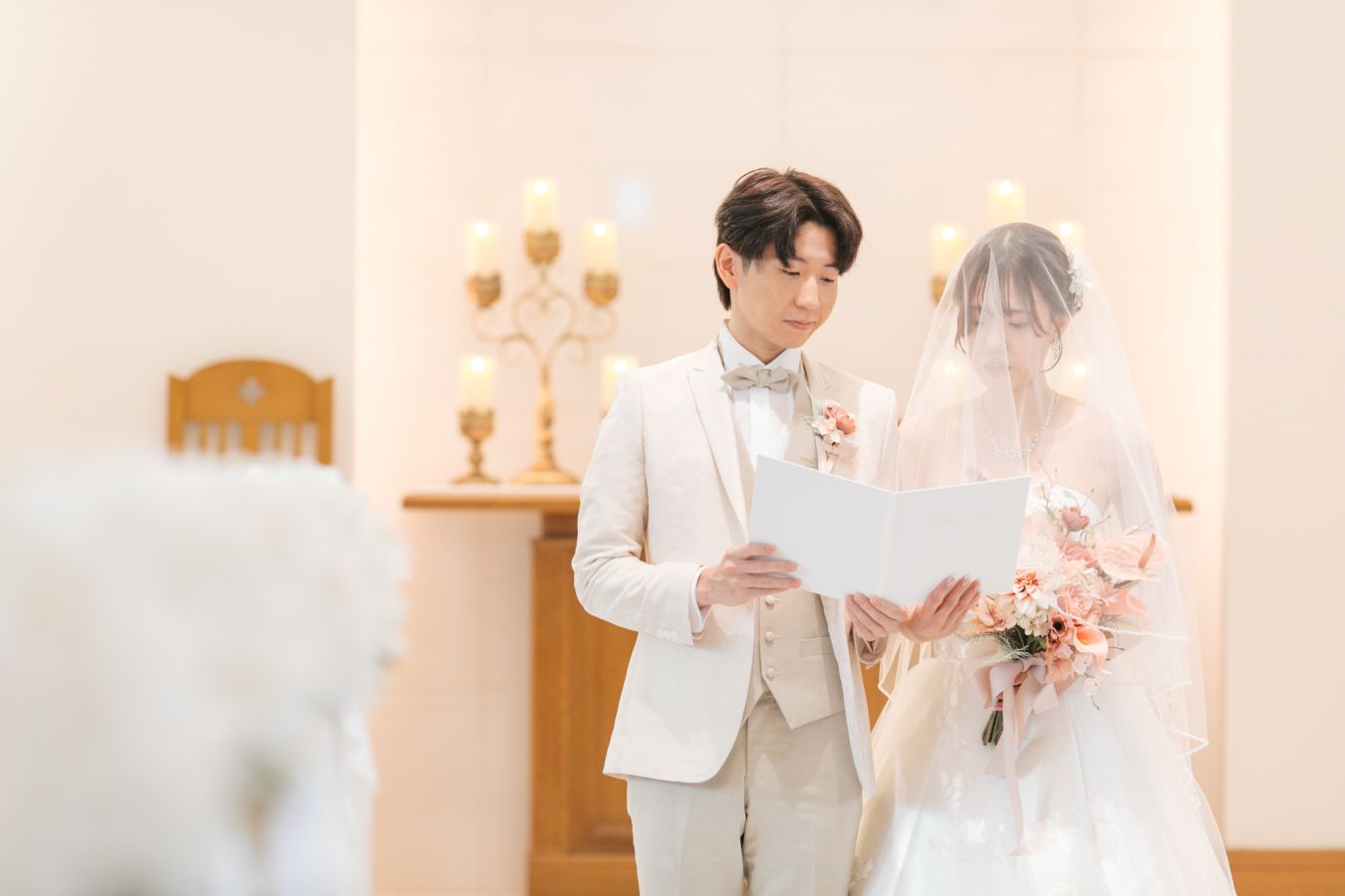 ANAクラウンプラザホテル松山でご結婚式を挙げられたお客様の写真　チャペルでご家族様の前で誓いの言葉を読まれるタキシードウェディングドレス姿の新郎新婦様