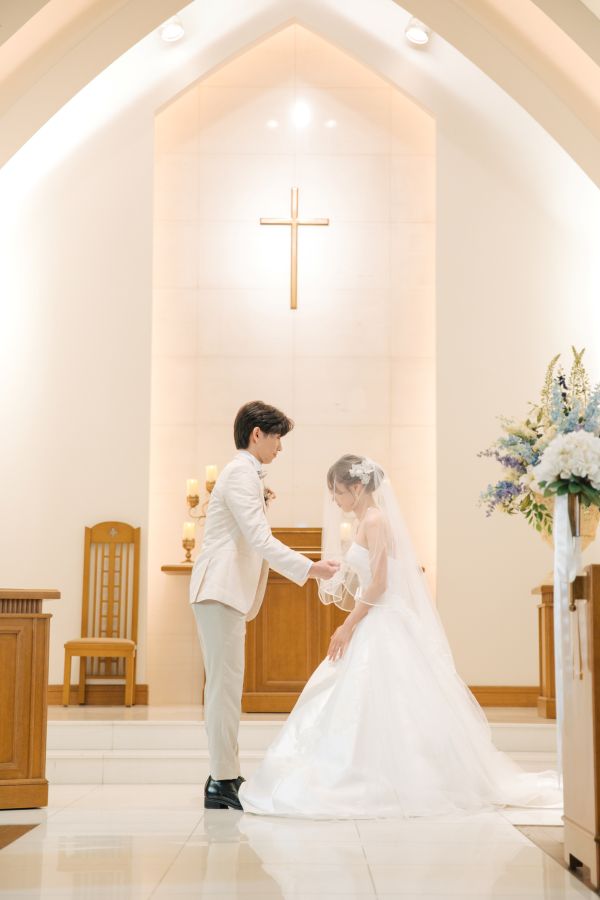 ANAクラウンプラザホテル松山でご結婚式を挙げられたお客様の写真　チャペルでタキシード姿の新郎様にベールアップをしてもらうウェディングドレス姿の新婦様
