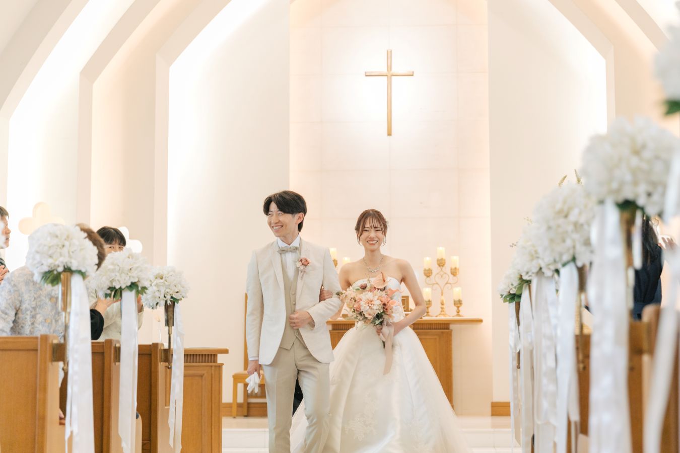 ANAクラウンプラザホテル松山でご結婚式を挙げられたお客様の写真　タキシードウェディングドレス姿の新郎新婦様が笑顔でチャペルから退場