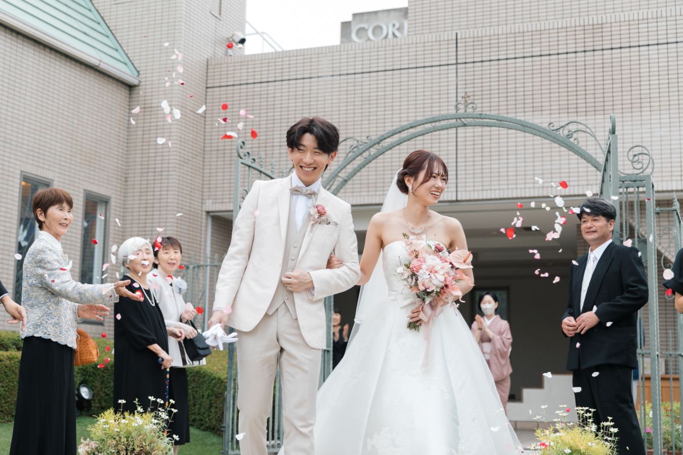 ANAクラウンプラザホテル松山でご結婚式を挙げられたお客様の写真　ガーデンでフラワーシャワーでご家族様から祝福を受けるタキシードウェディングドレス姿の新郎新婦様