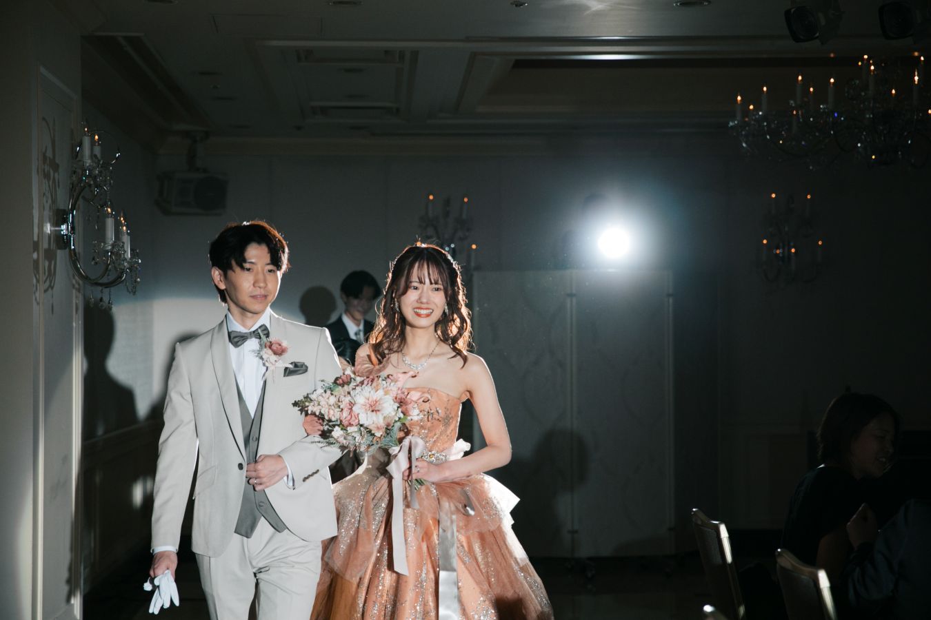 ANAクラウンプラザホテル松山でご結婚式を挙げられたお客様の写真　お色直しをしてタキシードカラードレス姿でお食事会場に入場されるスポットに照らされて新郎新婦様