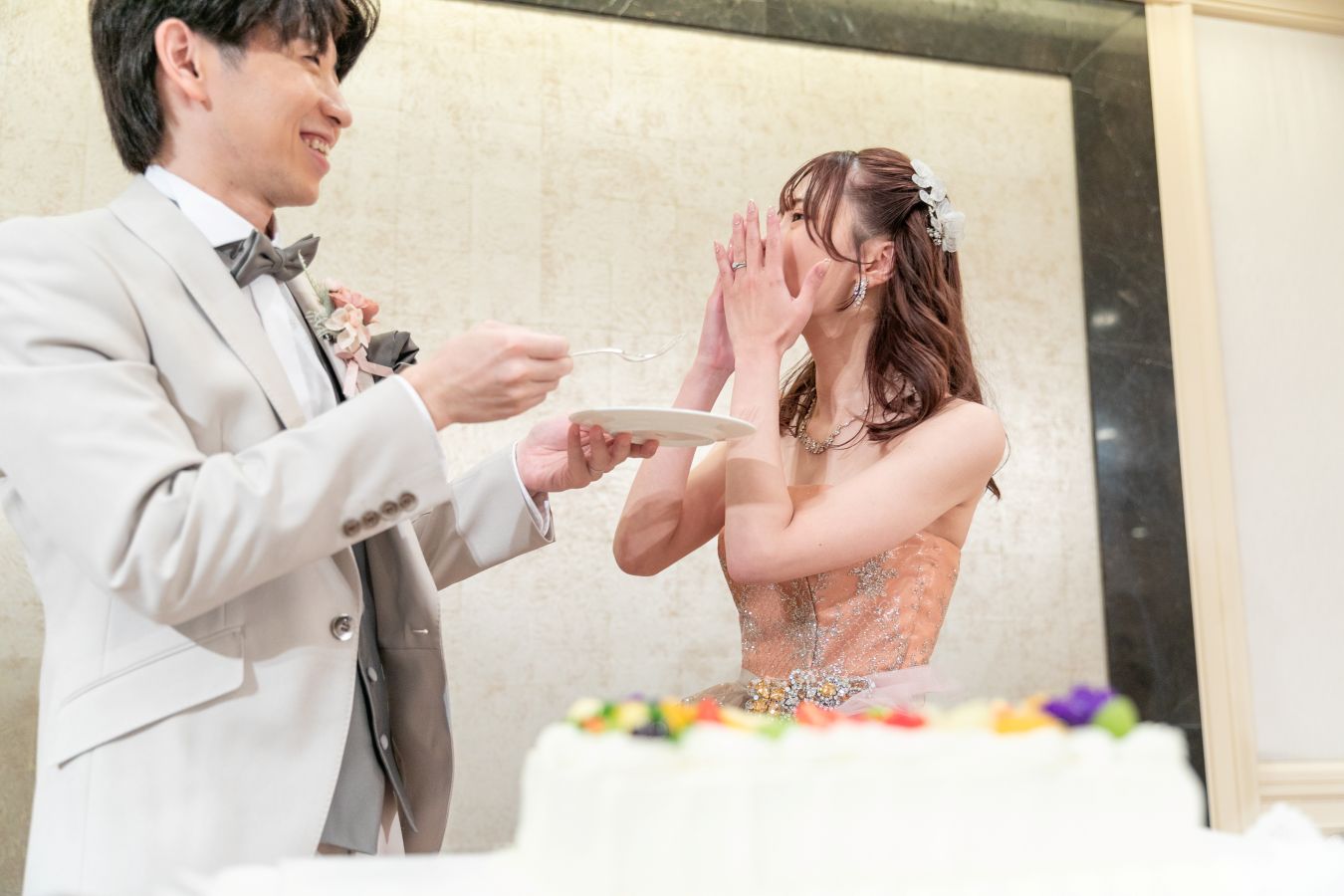 ANAクラウンプラザホテル松山でご結婚式を挙げられたお客様の写真　タキシードカラードレス姿の新郎新婦様がファーストバイトをしている写真