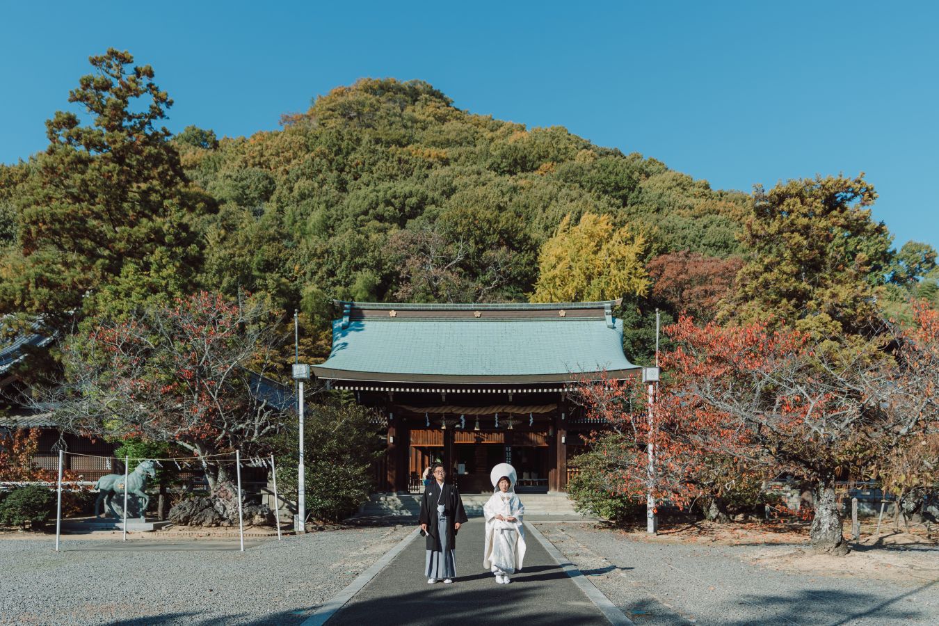 愛媛縣護國神社でご結婚式を挙げられたお客様の写真　境内で写真を撮る紋付袴白無垢姿の新郎新婦様