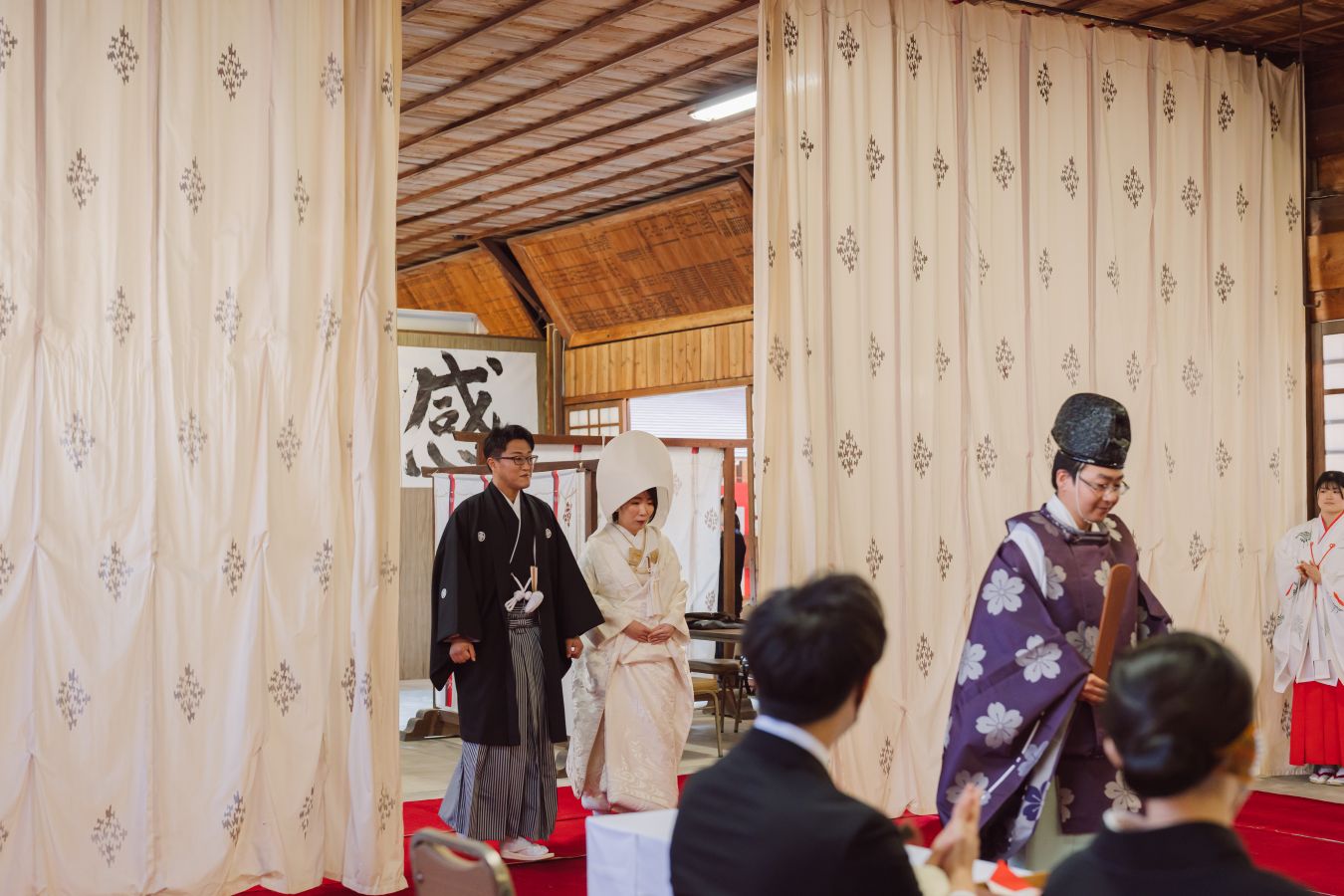 愛媛縣護國神社でご結婚式を挙げられたお客様の写真　ご家族様に拍手で迎えられる紋付袴白無垢姿の新郎新婦様