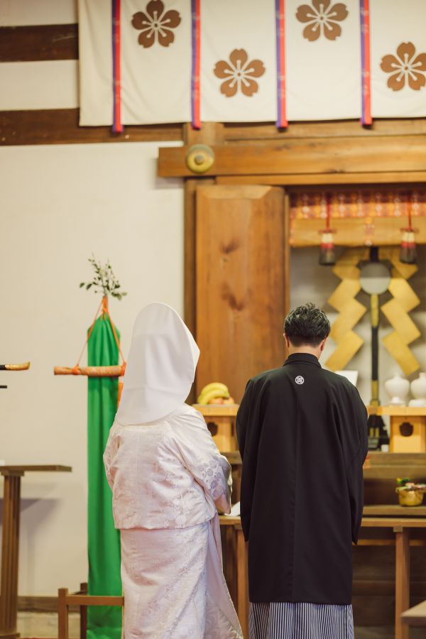 愛媛縣護國神社でご結婚式を挙げられたお客様の写真　誓いの言葉を読む紋付袴白無垢の新郎新婦様の後ろ姿