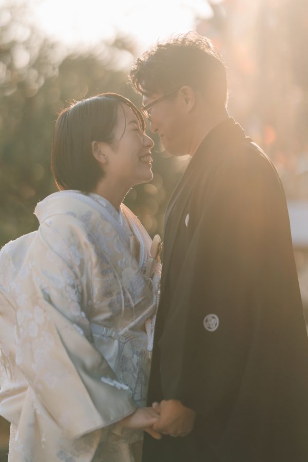 愛媛縣護國神社でご結婚式を挙げられたお客様の写真　夕日に照らされてお顔を寄せ合う紋付袴白無垢姿の新郎新婦様