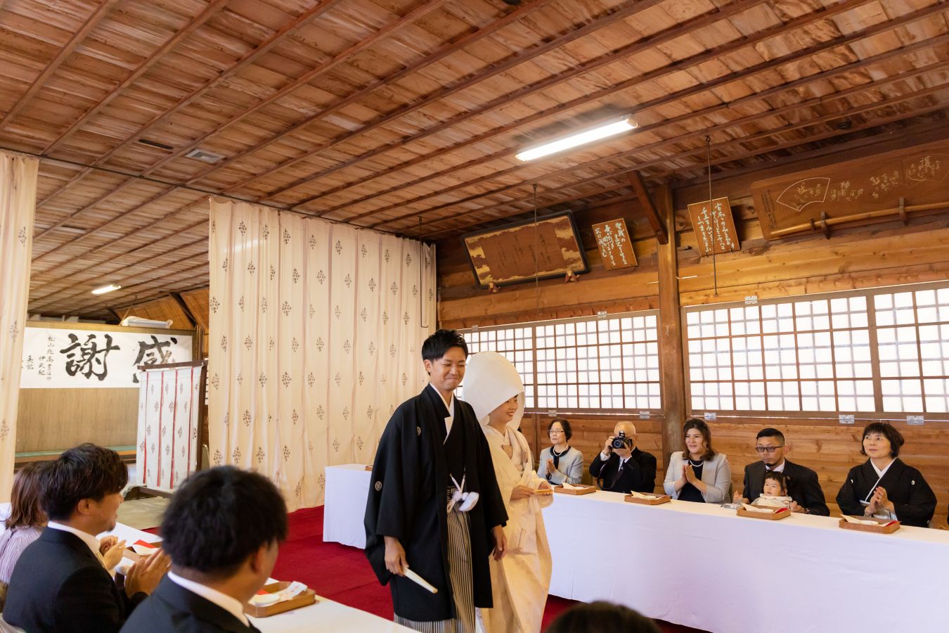 愛媛縣護國神社でご結婚式を挙げられたお客様の写真　ご家族様の拍手の中入場する新郎新婦様