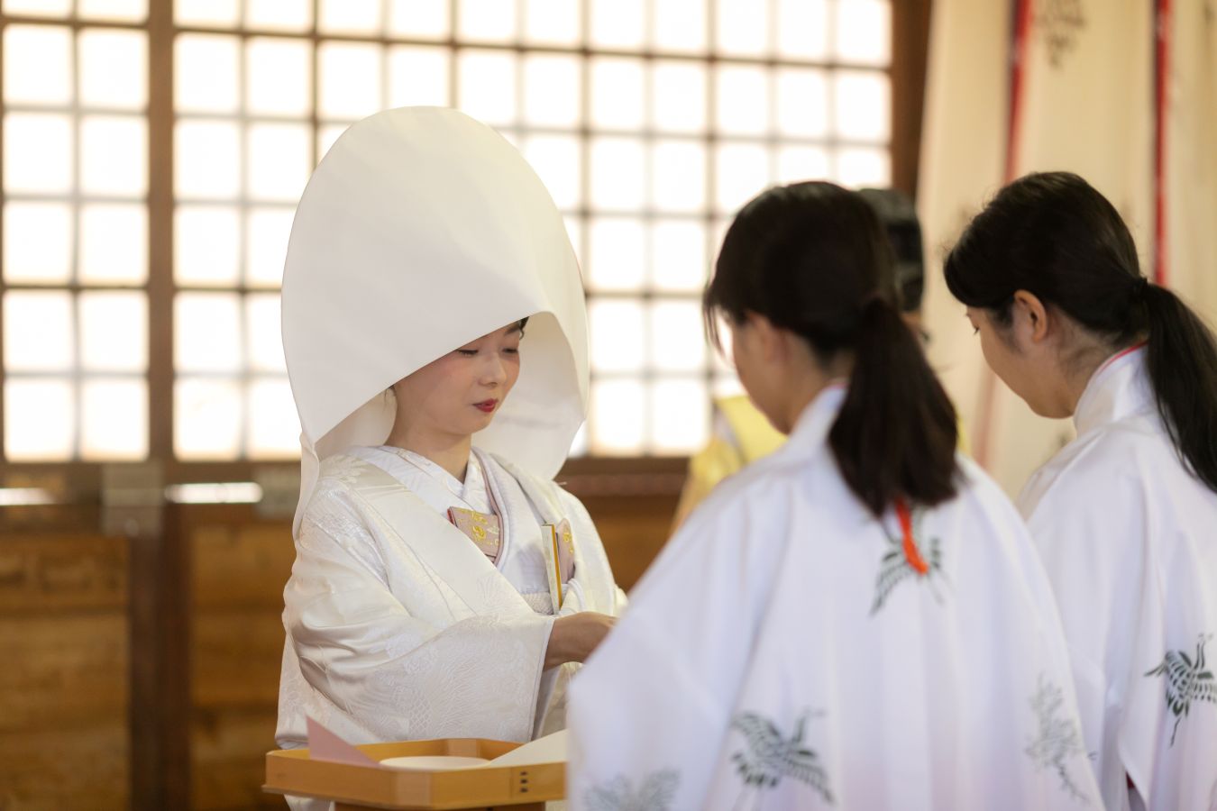 愛媛縣護國神社でご結婚式を挙げられたお客様の写真　三々九度のお酒を注いでもらっている白無垢姿の新婦様