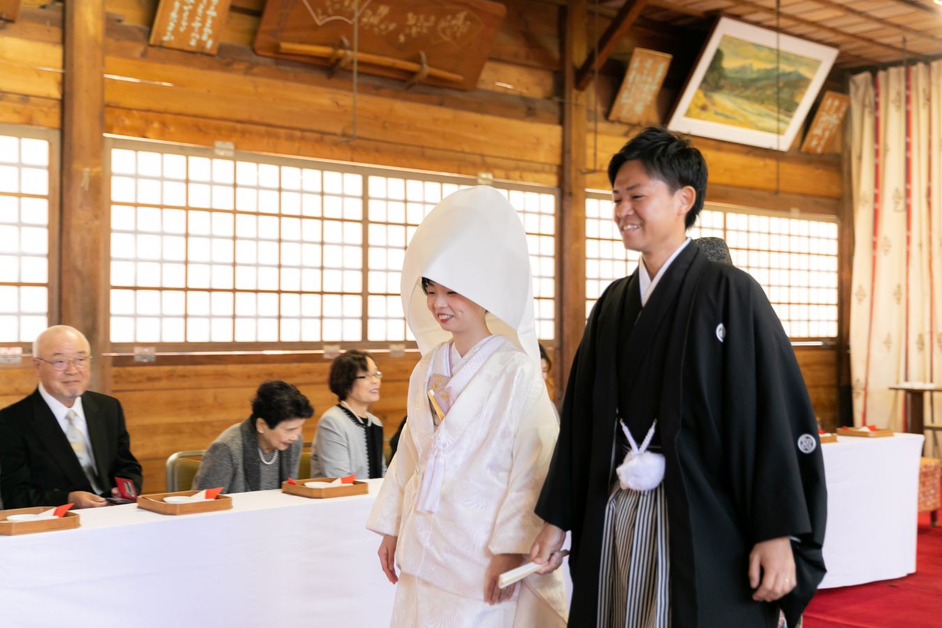 愛媛縣護國神社でご結婚式を挙げられたお客様の写真　神前式が結び安堵の表情でご退場される紋付袴白無垢姿の新郎新婦様