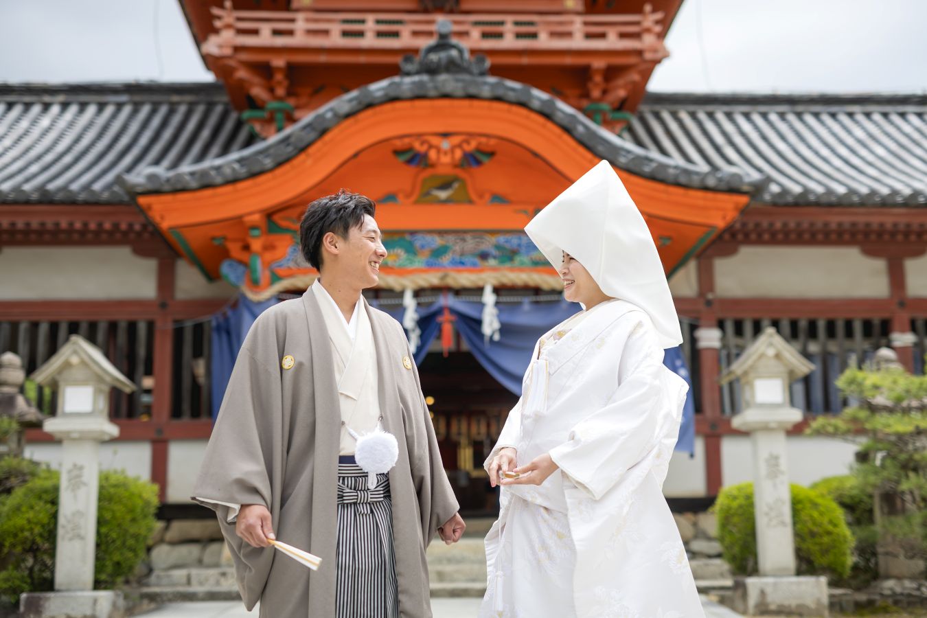 伊佐爾波神社でご結婚式後栴檀でお食事をされたお客様の写真　紋付袴白無垢綿帽子姿で神社の前で見つめあう新郎新婦様