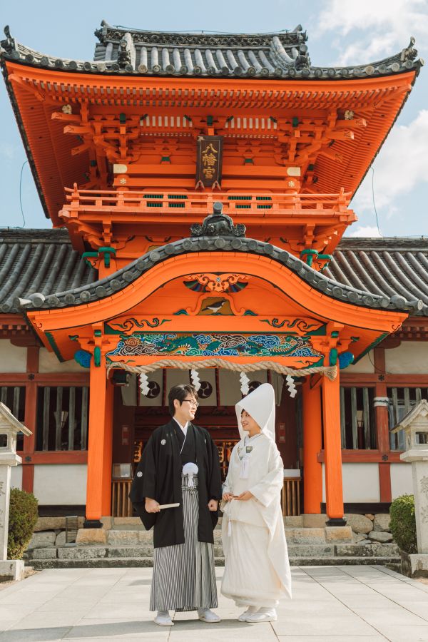 道後うめ乃やでご結婚式を挙げられたお客様の写真　青空の元神社の前でお写真を撮る新郎新婦様