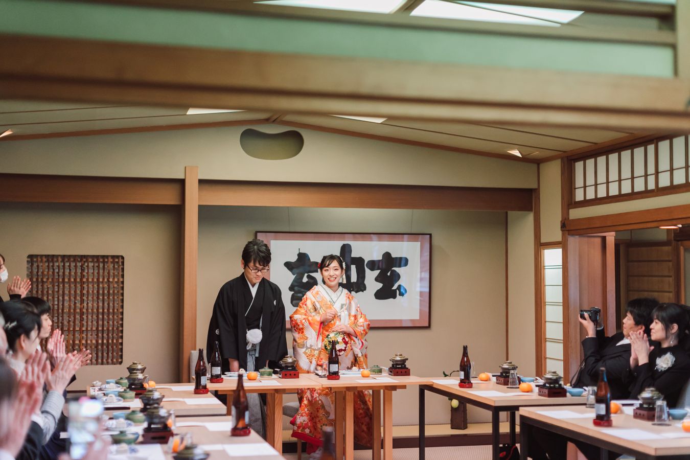 道後うめ乃やでご結婚式を挙げられたお客様の写真　お二人がご入場され、拍手で迎えられる紋付袴色打掛姿の新郎新婦様