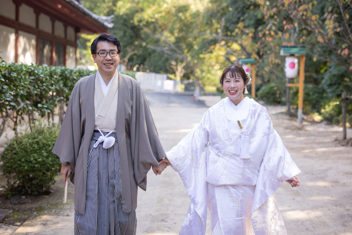 伊佐爾波神社で挙げられたお客様の結婚式写真　駐車場から境内まで仲良く手をつないで歩いてこられる紋付袴白無垢姿の新郎新婦様