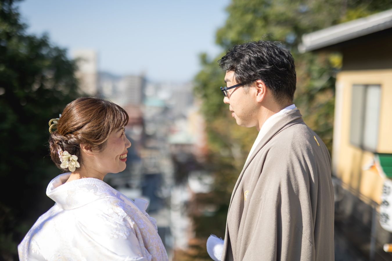 伊佐爾波神社で挙げられたお客様の結婚式写真　道後の街背景に見つめあう紋付袴白無垢姿の新郎新婦様