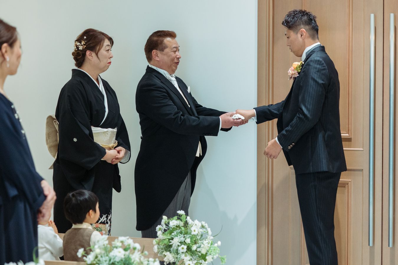 小さな結婚式 松山チャペルで挙げられたお客様の結婚式写真　新郎様のご入場　お母様からジャケットを着せてもらいお父様からグローブを受け取る新郎様