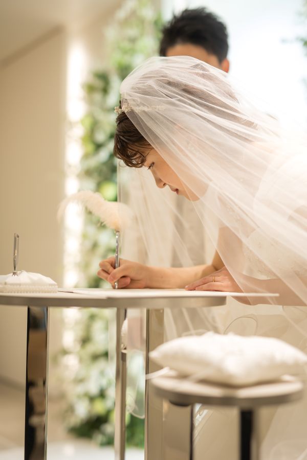 小さな結婚式 松山チャペルで挙げられたお客様の結婚式写真　結婚誓約書にサインを書くウェディングドレス姿の新婦様