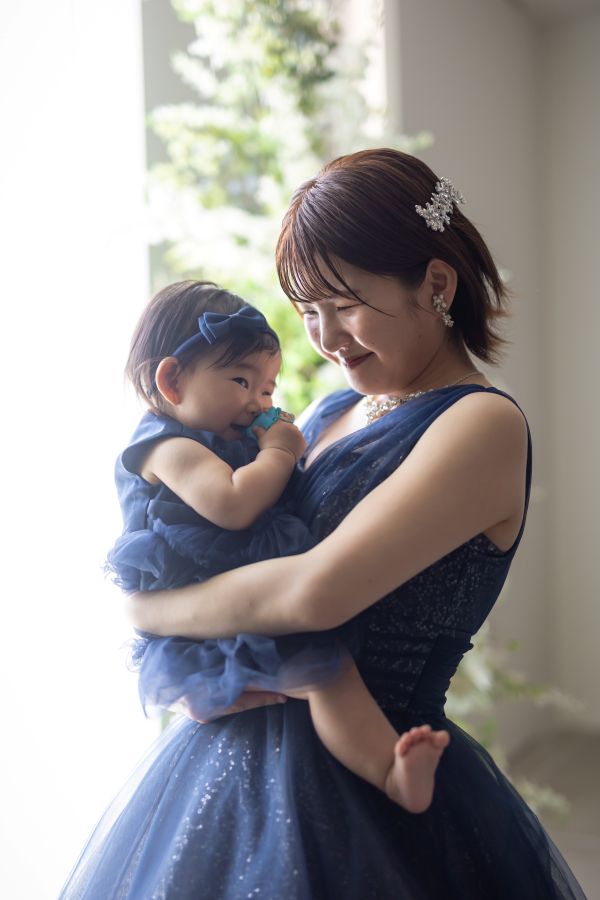 松山スタジオで撮影された新郎新婦様のお写真　新婦様に抱っこしてもらって嬉しそうなお子様と愛おしそうにみつめる新婦様