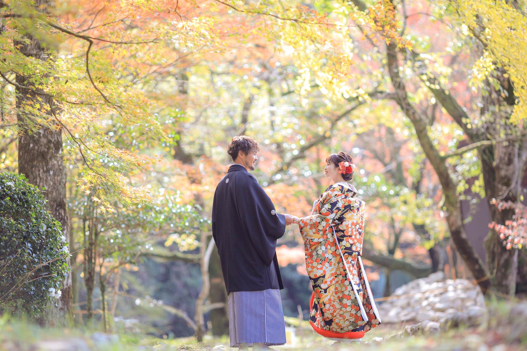 紅葉に包まれ手を取り合う2人