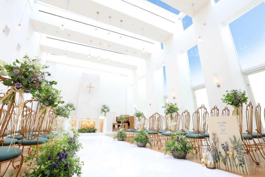 純白の空間に自然光が溢れるチャペル エンジェル。 高い天井に設けられたガラス窓には青空が映り、こぼれるようにキラキラと太陽の光が降り注ぎます