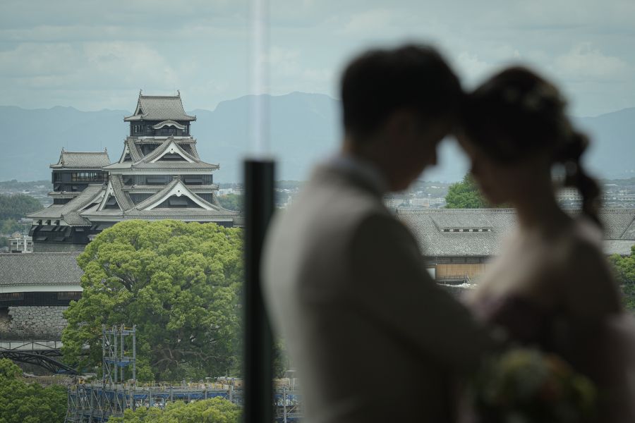熊本市中央区桜町の複合施設「サクラマチ クマモト」に隣接する「KOKO HOTEL Premier 熊本」の最上階14階に位置しています。中心市街地の最も利便性の高いエリアに位置しながら、天空の開放感を楽しめる抜群のロケーションです。店内の大きなガラス窓からは、熊本のシンボルである熊本城の天守閣や城郭を上空から見下ろすように一望できます。天気が良い日には熊本市街の街並みの向こうに阿蘇の山々まで見渡せ、熊本のダイナミックな自然美と城下町の歴史を感じられます。